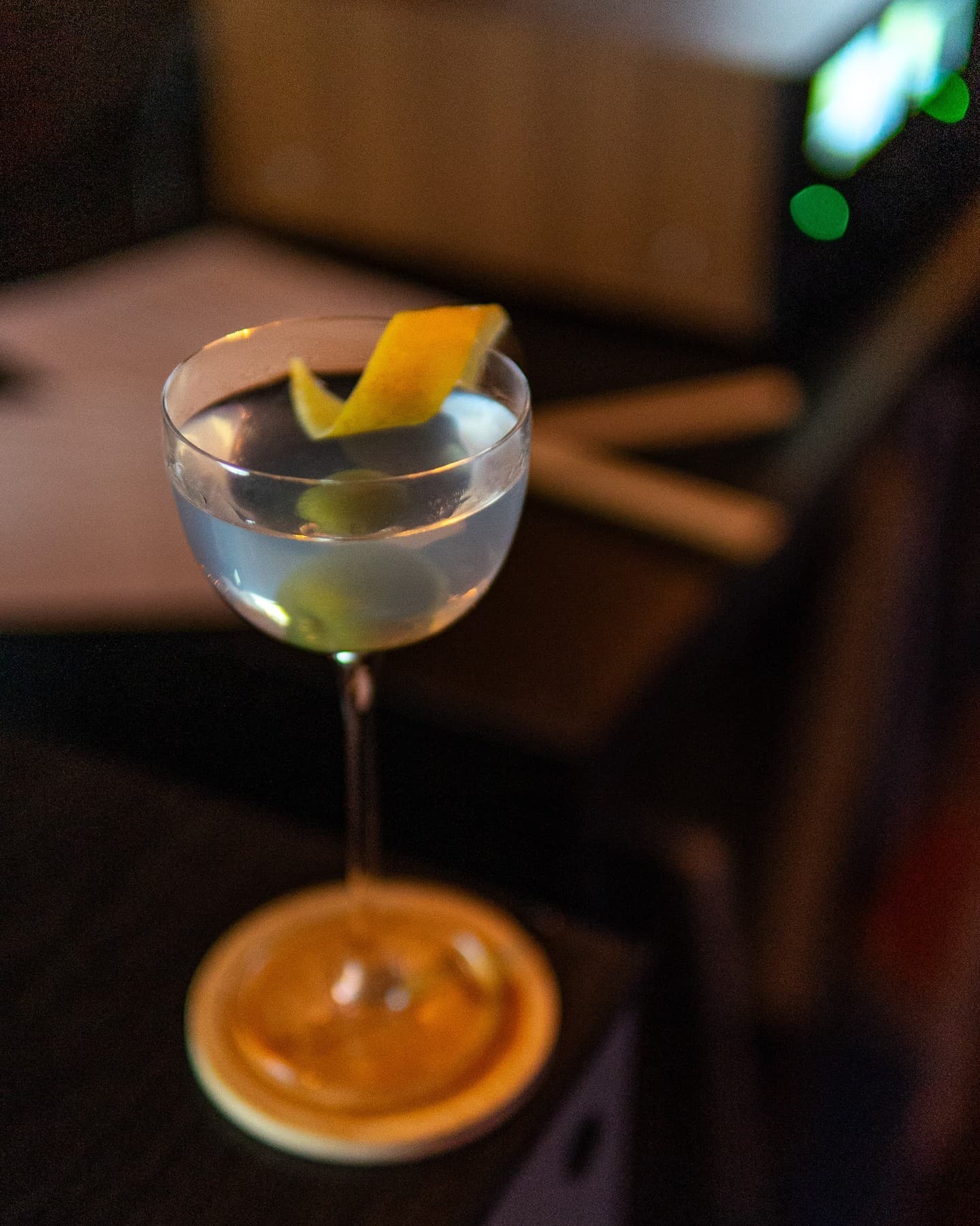 A martini with a lemon twist glowing against the dark room